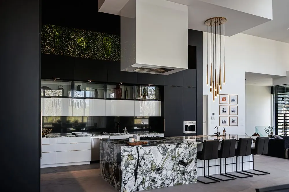 Black kitchen with a marble island under a ceiling over 20 feet high