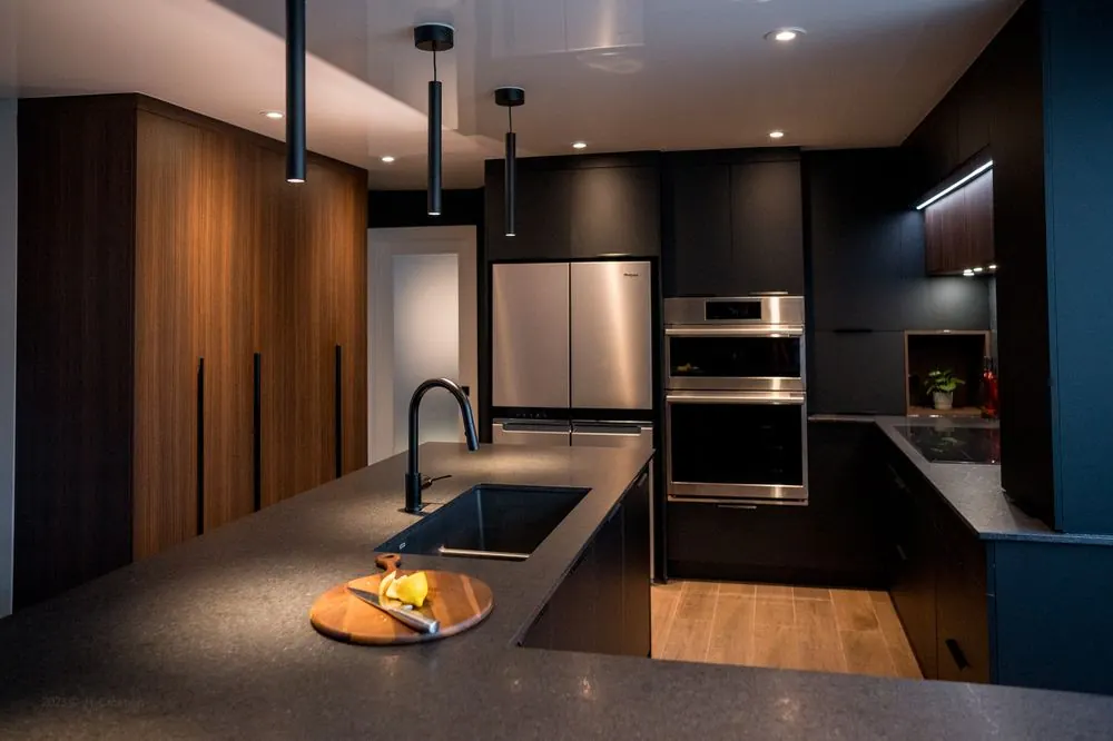 Black kitchen with a white stretch ceiling and walnut cabinetry