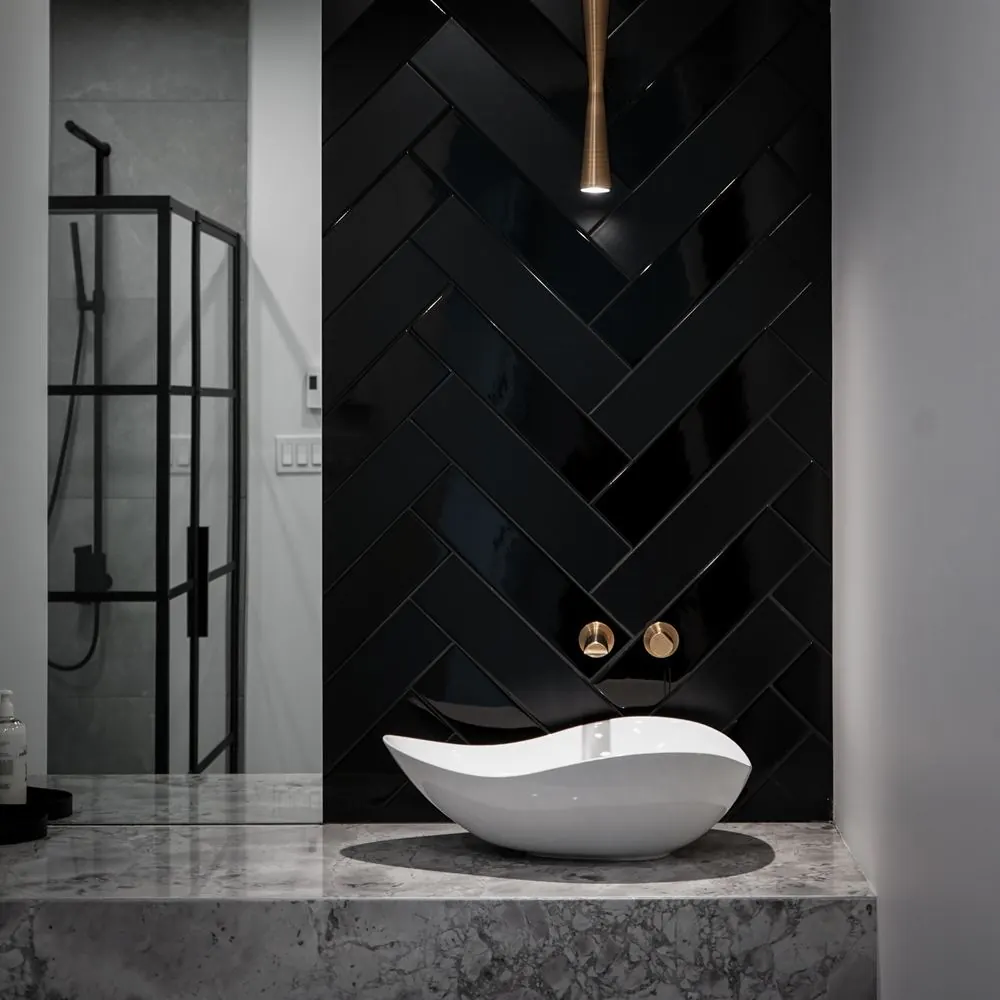 Bathroom with black herringbone tile and a sculptural basin
